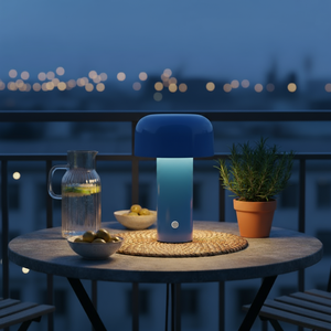 Glowing blue lamp, a glass pitcher of water, bowls of olives, and a potted herb on a table