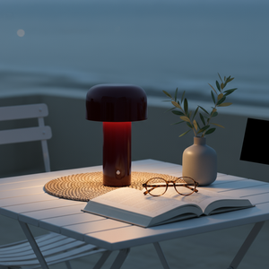 Table with lamp, book, glasses, and vase by the sea at night