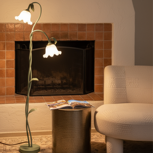Floor lamp with floral design next to a fireplace and chair in a cozy room.