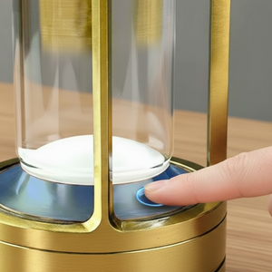 Hand pressing a button on a gold and glass device with a gray background