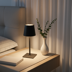 Lamp on a bedside table with a vase and plant in a bedroom setting