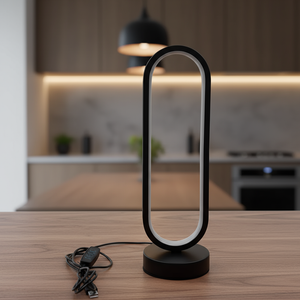 Modern black table lamp on a wooden surface with a blurred kitchen background