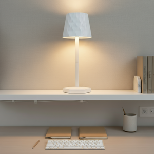White table lamp on a shelf with a minimalistic setup including a keyboard and books.