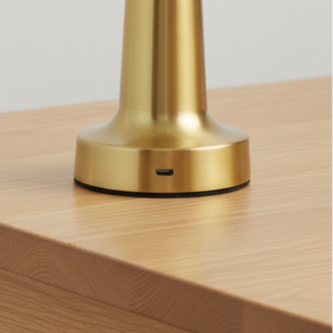 Gold pendant light on a wooden table with a plain background