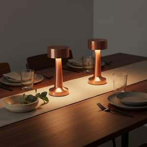 Two copper-colored table lamps on a dining table with plates and glasses.