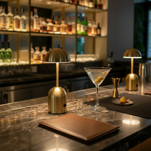 Bar counter with a cocktail, gold lamp, and menu in a dimly lit bar setting.