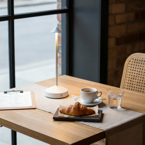 Table with coffee, croissant, and glass of water in a cozy setting.
