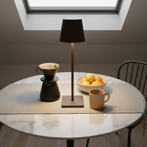 Round marble table with a lamp, coffee maker, and bowl of fruit in a modern room.