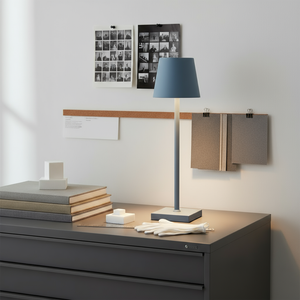 Modern desk setup with a lamp, books, and gloves in a minimalistic office setting.