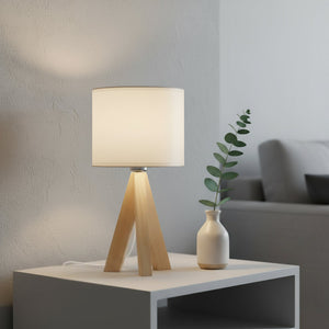 Table lamp with wooden base and white shade on a side table in a living room setting.
