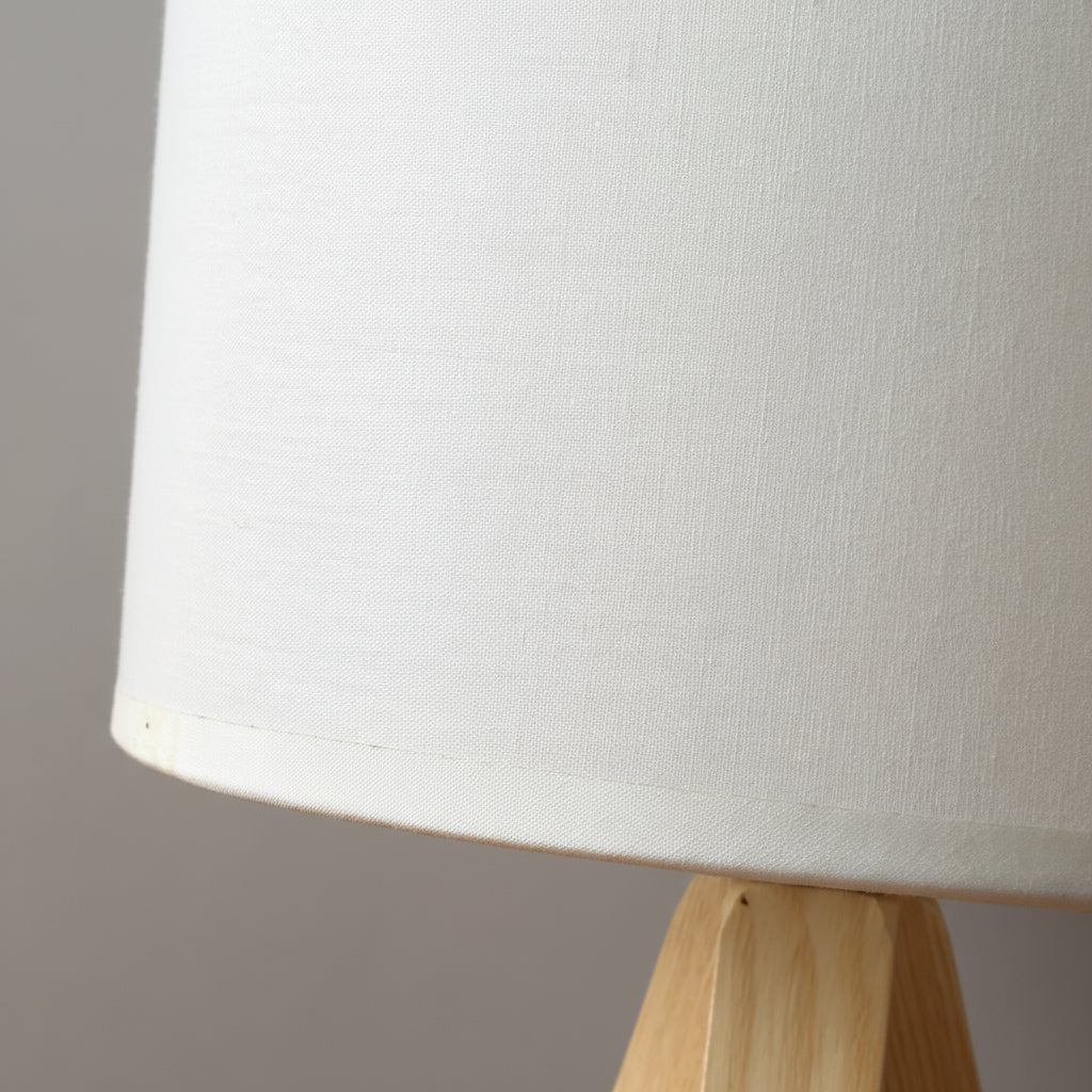 Close-up of a white lampshade on a wooden base against a gray background