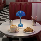 Table setting with a cup of coffee, cookies, and a blue lamp in a retro-style diner.