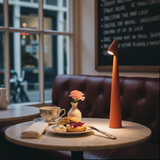 Table setting with a plate of food, teacup, and vase in a cafe.