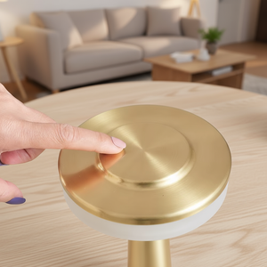 Gold and white cylindrical object on a wooden table with a hand interacting with it, in a living room setting.