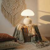 White lamp on a woven basket with a macrame wall hanging in the background