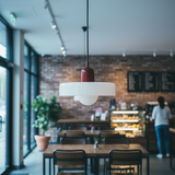 Interior of a modern cafe with wooden tables, chairs, and a hanging light fixture.