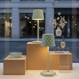 Decorative lamps and vases on wooden and glass stands with a blurred indoor background.
