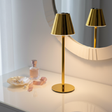 Dining table set with gold lamps, wine glasses, and a bowl of fruit against a cityscape background.