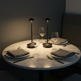Dining table set with plates, glasses, and cutlery in a dimly lit room.